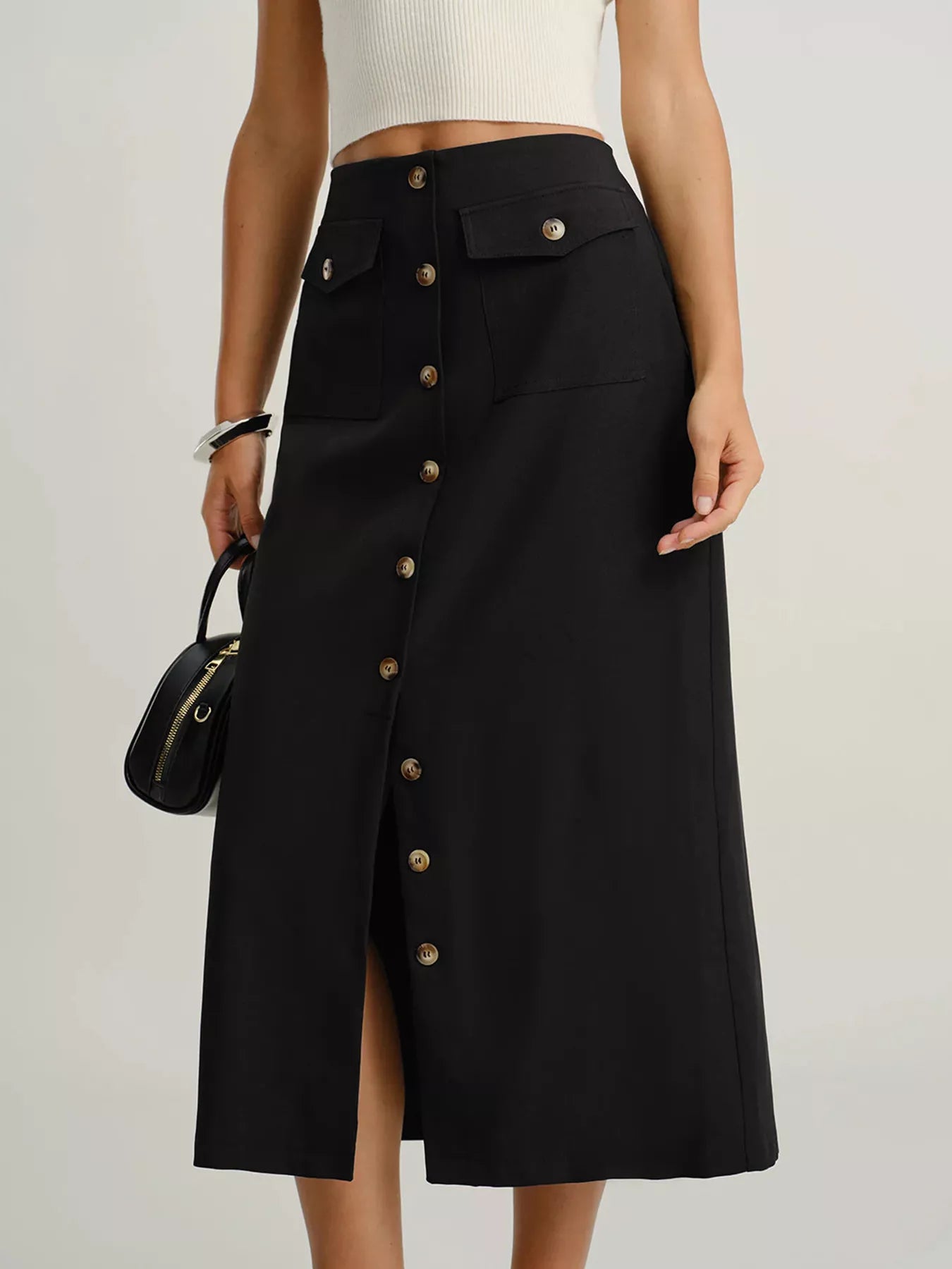 Black midi skirt with button front, flap pockets, and a front slit.