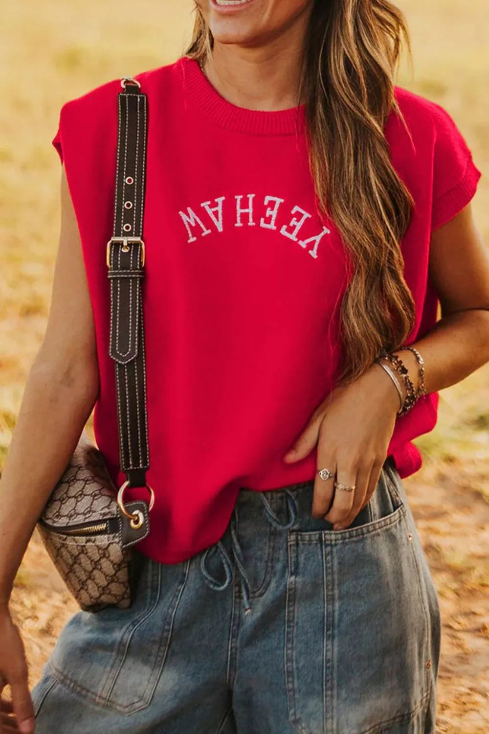 Red crew neck sweater vest with white embroidered text, sleeveless, casual style