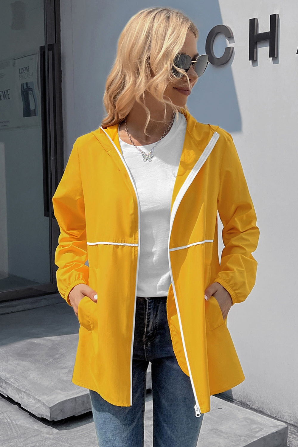 Yellow hooded rain coat with white trim and zipper, worn open over a white t-shirt.