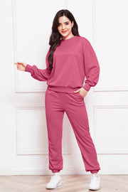 Relaxed fit loungewear set in hot pink, featuring a crewneck sweatshirt and jogger pants with pockets.