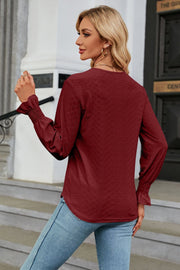 Burgundy textured V-neck blouse with smocked cuffs and long sleeves.