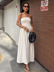 Beige smocked bodice relaxed maxi dress with a strapless neckline and textured fabric.