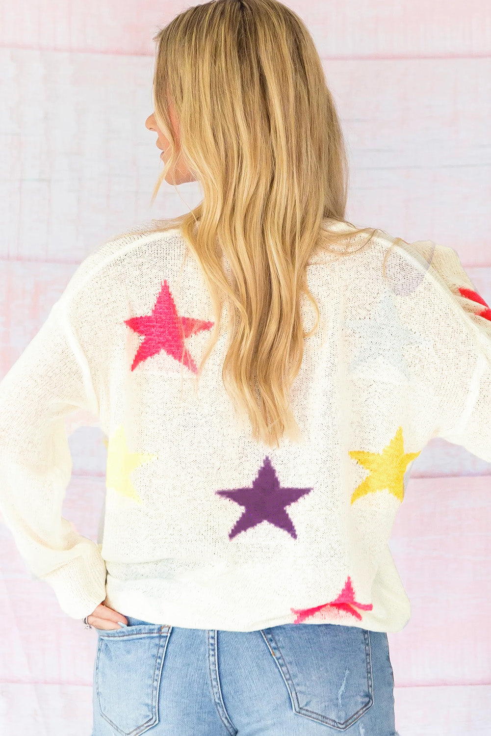 White knit sweater with colorful starburst pattern, long sleeves, casual fit.