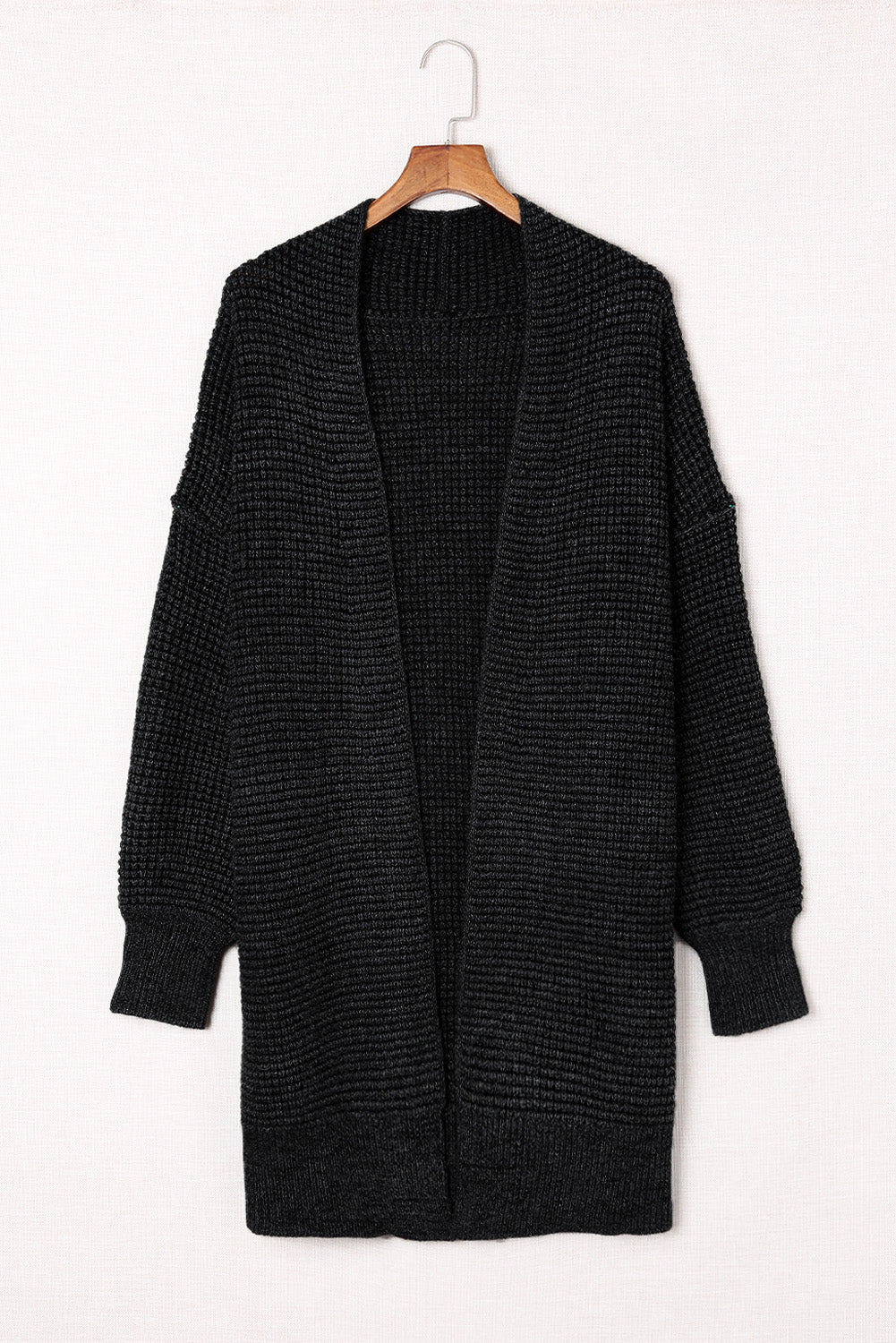Black textured acrylic open cardigan with puff sleeves and a waffle knit.