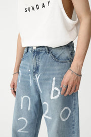 Medium wash baggy jeans with white painted script detail, casual style.