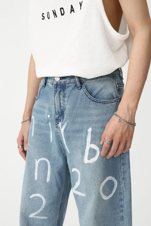 Medium wash baggy jeans with white painted script detail, casual style.