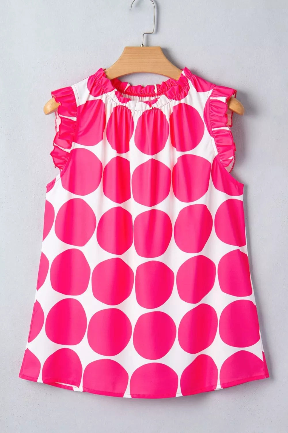 White polyester tank top with large pink polka dots and frill neckline and sleeves.