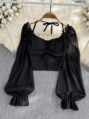 Black Swiss dot maternity blouse with sweetheart neckline, ruffled long sleeves, and halter tie.