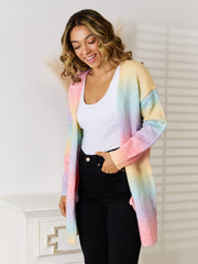 Longline knit cardigan with rainbow gradient pattern in pastel pink, yellow, blue, and purple.