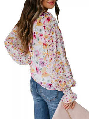Vibrant floral print blouse with tie detail, long sleeves, and smocked cuffs.