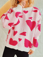 Pink knit sweater with hot pink heart pattern, crewneck, long sleeves, and white cuffs and hem.