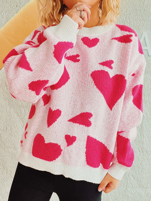 Pink knit sweater with hot pink heart pattern, crewneck, long sleeves, and white cuffs and hem.