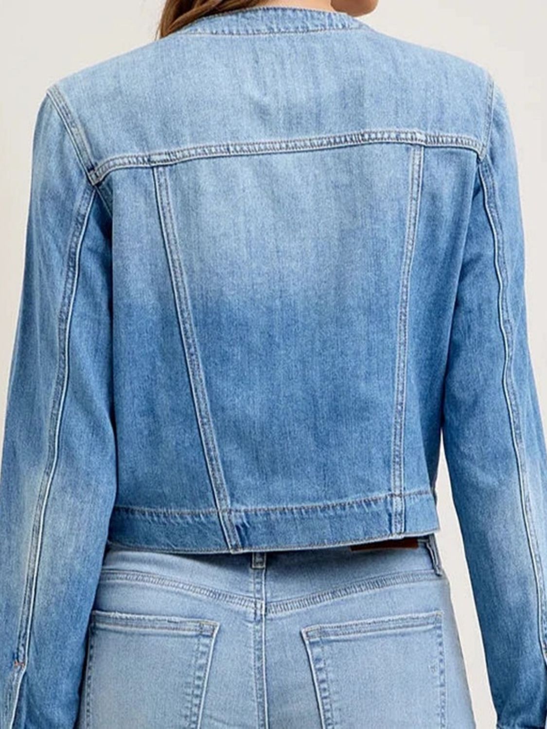 Light wash denim trucker jacket with band collar and buttoned cuffs.
