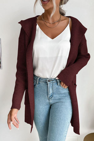 Burgundy ribbed knit hooded cardigan with drape front and pockets, worn open over a white cami and jeans.