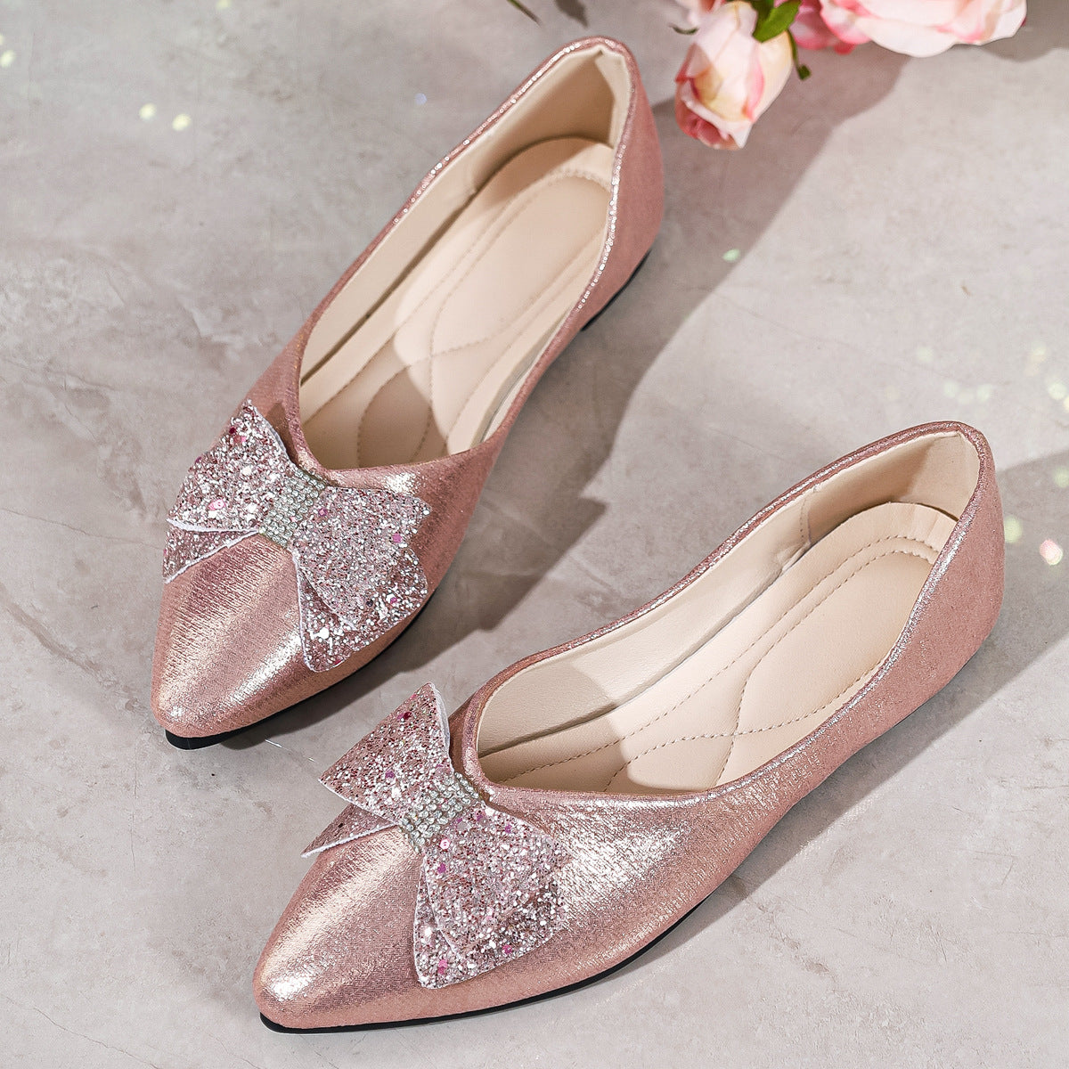 Pink pointed toe flats with glitter bows and rhinestone accents.