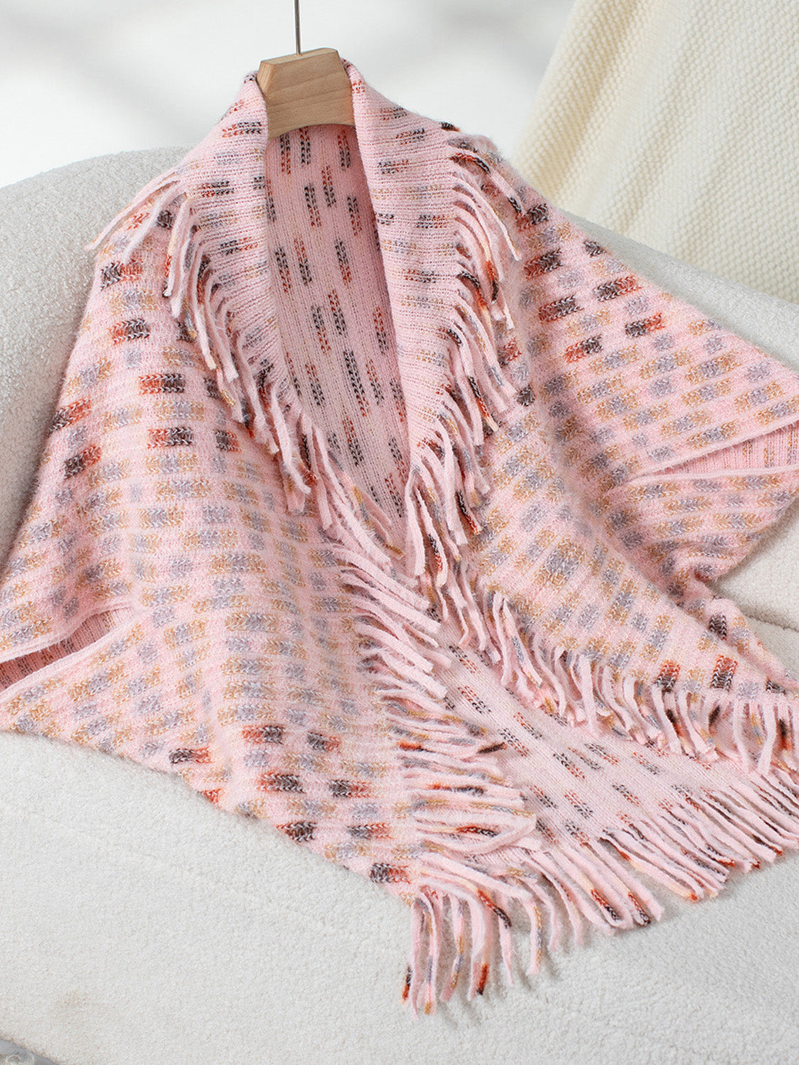 Blush pink acrylic shawl cardigan with textured pattern and fringe details
