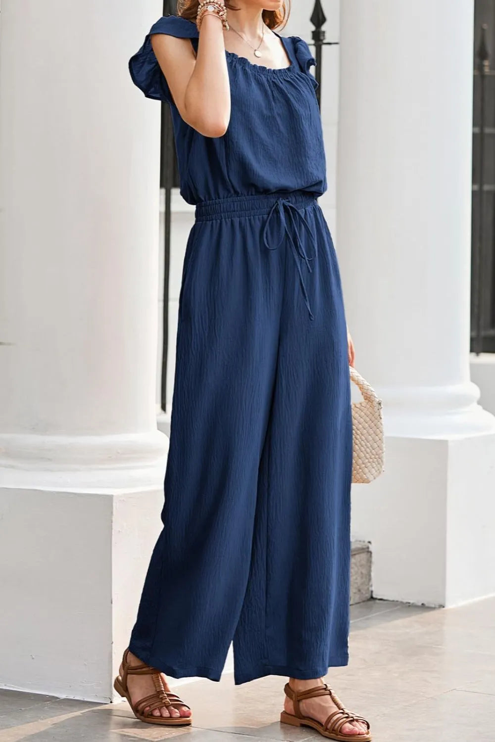 Dark Blue Textured Ruffle-Sleeve Drawstring Palazzo Jumpsuit with wide legs and square neckline.