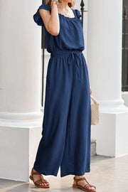 Dark Blue Textured Ruffle-Sleeve Drawstring Palazzo Jumpsuit with wide legs and square neckline.