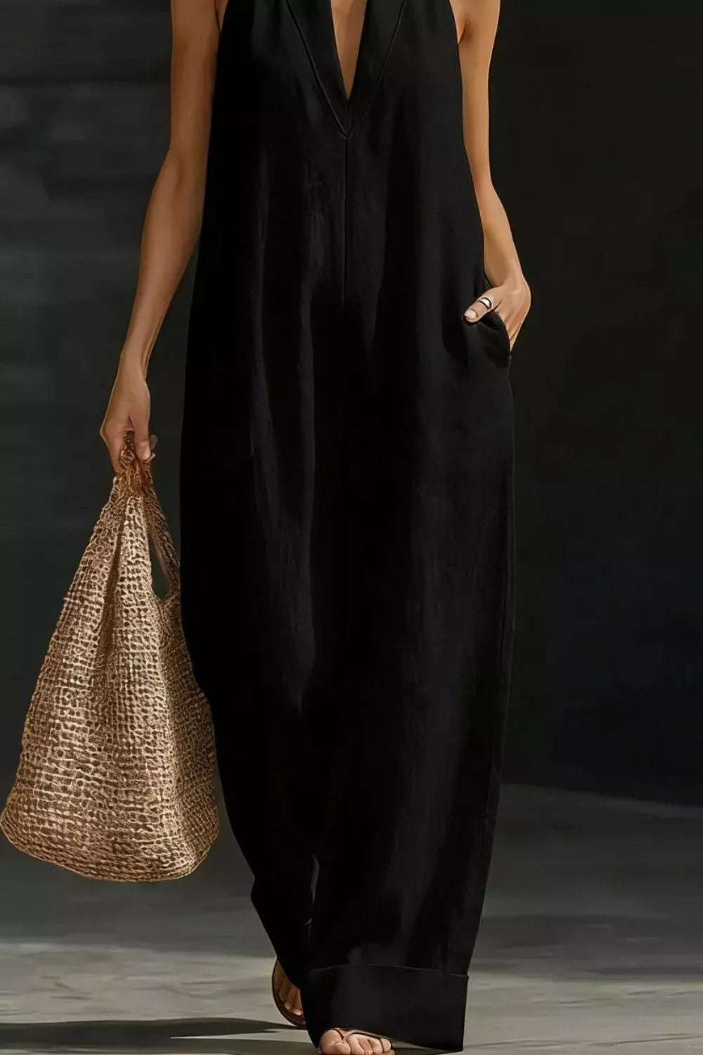 Black halter-neck maternity jumpsuit with pockets, v-neck, and wide legs.