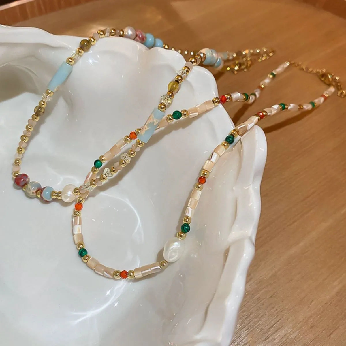Multi-strand gemstone collar necklace with beads, pearls, and gold accents.