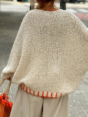 Cream knit sweater with orange trim, V-neck, relaxed fit, acrylic.