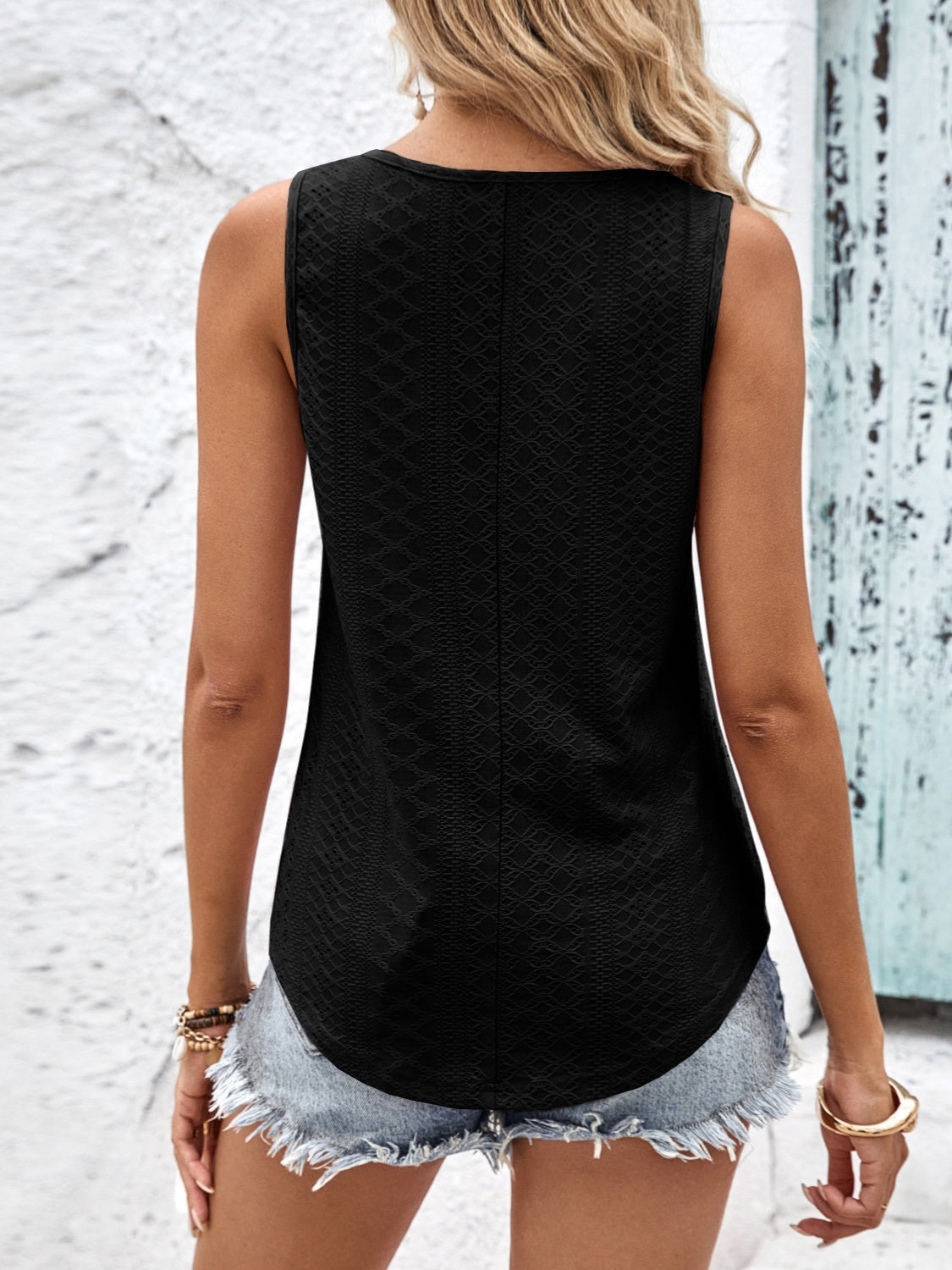 Black eyelet tank top with a textured pattern and curved hem.