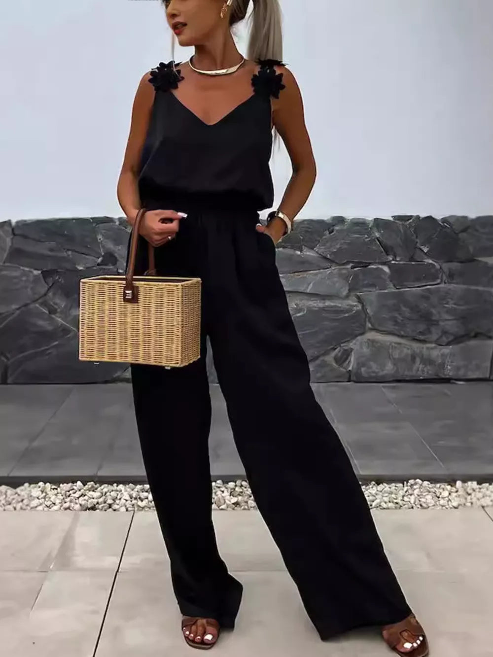 Black wide-leg jumpsuit with floral applique straps and V-neck.
