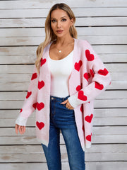 Pink acrylic knit cardigan with red heart intarsia pattern and white cuffs.