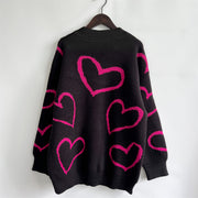 Black acrylic knit sweater with a pink heart outline pattern and mock neck.