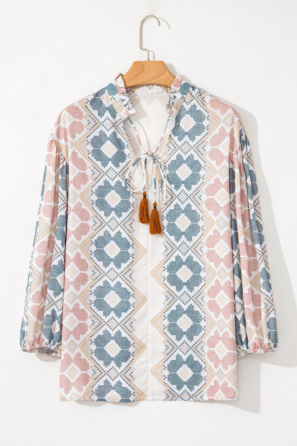Floral geometric print blouse with tassel tie neckline and ruffled collar.