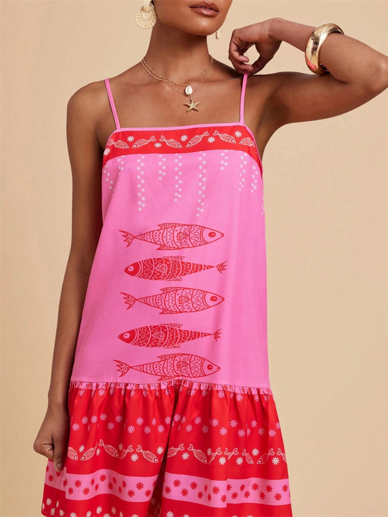 Pink spaghetti strap mini dress with red fish print and tiered ruffle hem.