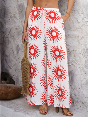 Geometric print wide-leg trousers in white with red suns, drawstring waist, and pockets.