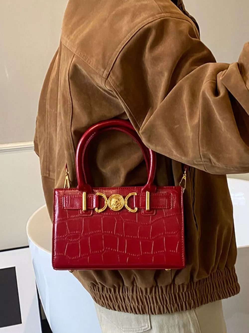 Red crocodile-textured crossbody bag with gold hardware and top handle.