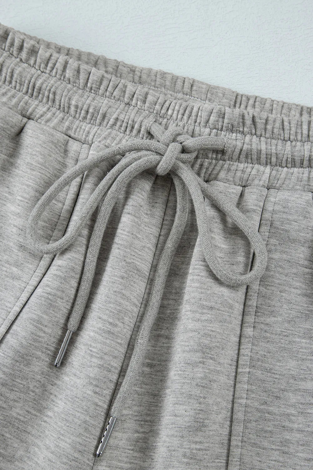 Gray wide-leg lounge trousers with elastic waistband and drawstring detail.