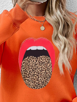 Orange sweatshirt with bold red lips and leopard tongue graphic.