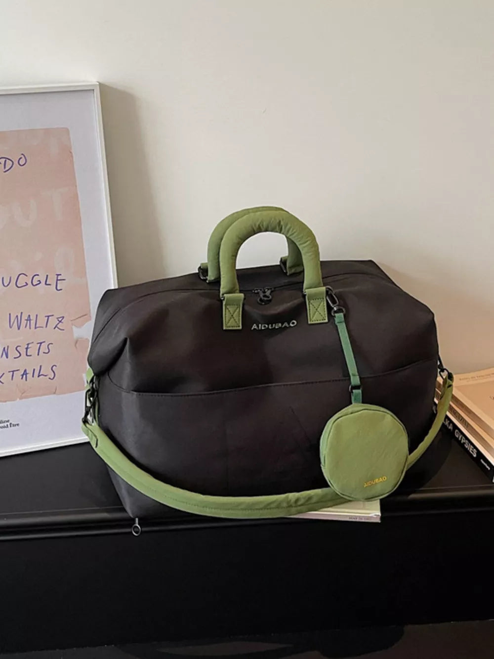 Black nylon duffle bag with green handles and strap, includes detachable pouch