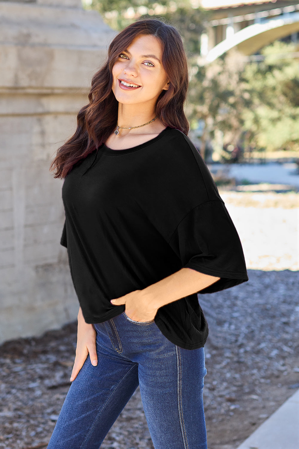 Black boxy dolman crop t-shirt with wide sleeves and a scoop neck, styled with jeans.
