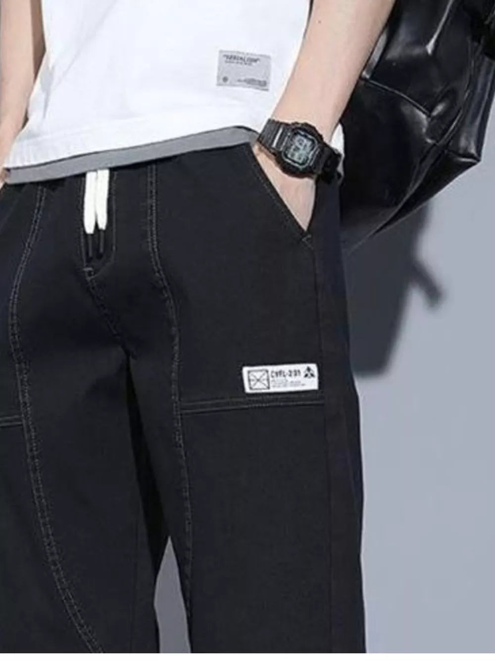Black drawstring jogger jeans with white laces and a patch detail.