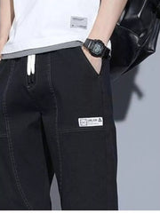 Black drawstring jogger jeans with white laces and a patch detail.