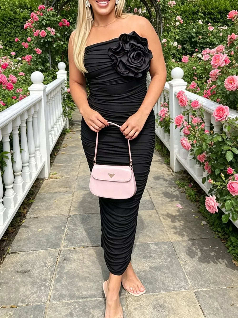 Black ruched bodycon midi dress with floral appliqué detail and strapless neckline.