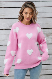 Hot pink crewneck sweater with white heart appliqués, casual acrylic knit.