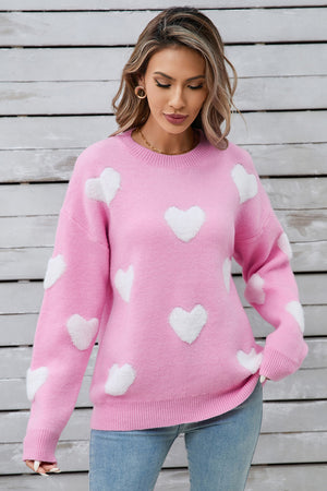 Hot pink crewneck sweater with white heart appliqués, casual acrylic knit.