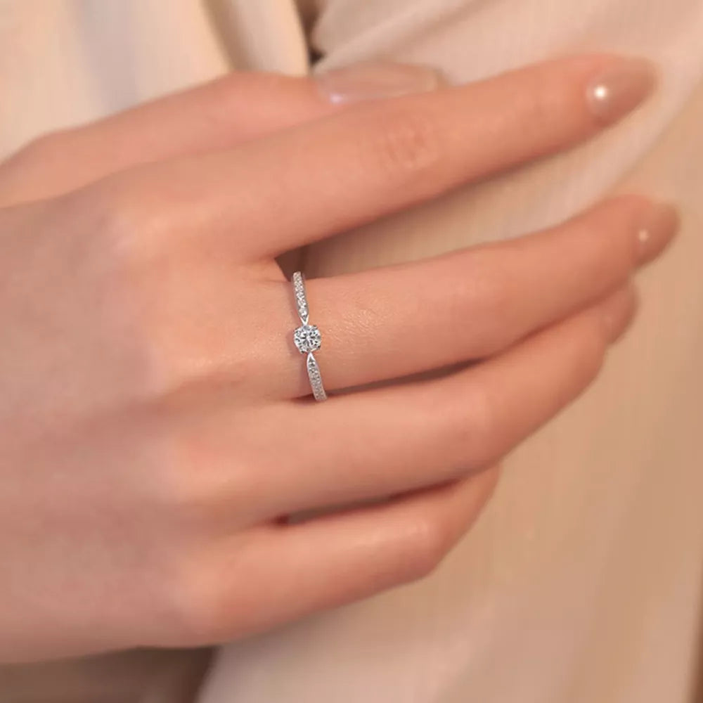Elegant moissanite ring in sterling silver with a brilliant center stone and pave band.