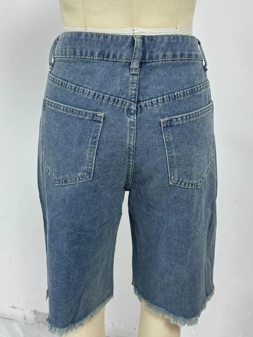 Blue denim bermuda shorts with frayed hem and relaxed fit.