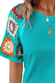 Teal t-shirt with short granny square crochet sleeves in multicolor.