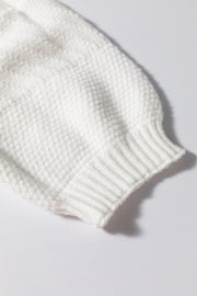 White cable knit sweater sleeve with ribbed cuff and diamond texture detail