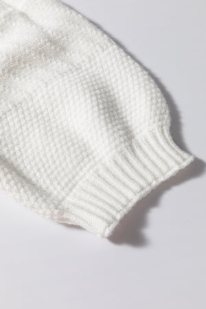 White cable knit sweater sleeve with ribbed cuff and diamond texture detail