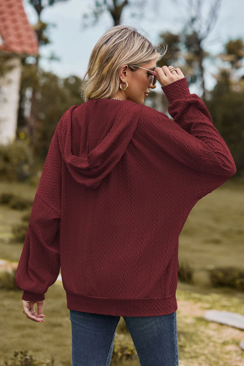 Burgundy textured cable knit hoodie with a relaxed fit and dolman sleeves.