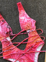 Snakeskin plunge swimsuit with crisscross straps in hot pink and orange gradient.