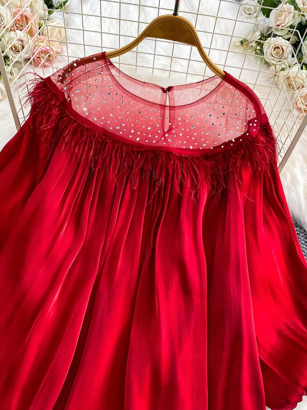 Red sheer blouse with rhinestone embellishments and feather trim neckline.